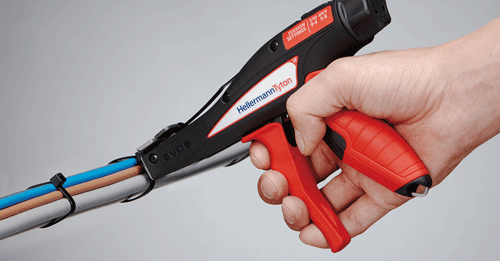 Eine Person hält ein Gerät von HellermannTyton an Kabel und verbindet diese mit Kabelbindern