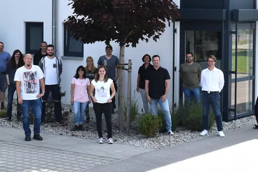 rolf weigel Jubiläum mit einem Gruppenbild der Mitarbeiter vor dem Gebäude