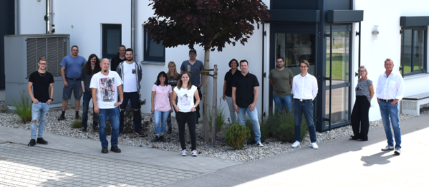 rolf weigel Jubiläum mit einem Gruppenbild der Mitarbeiter vor dem Gebäude