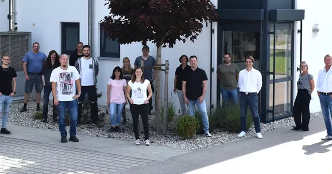 rolf weigel Jubiläum mit einem Gruppenbild der Mitarbeiter vor dem Gebäude