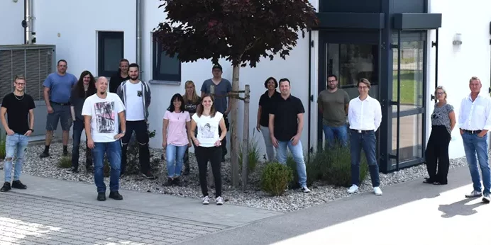 rolf weigel Jubiläum mit einem Gruppenbild der Mitarbeiter vor dem Gebäude