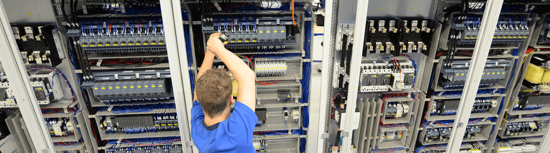 Ein Mann schraubt an einem Schaltschrank