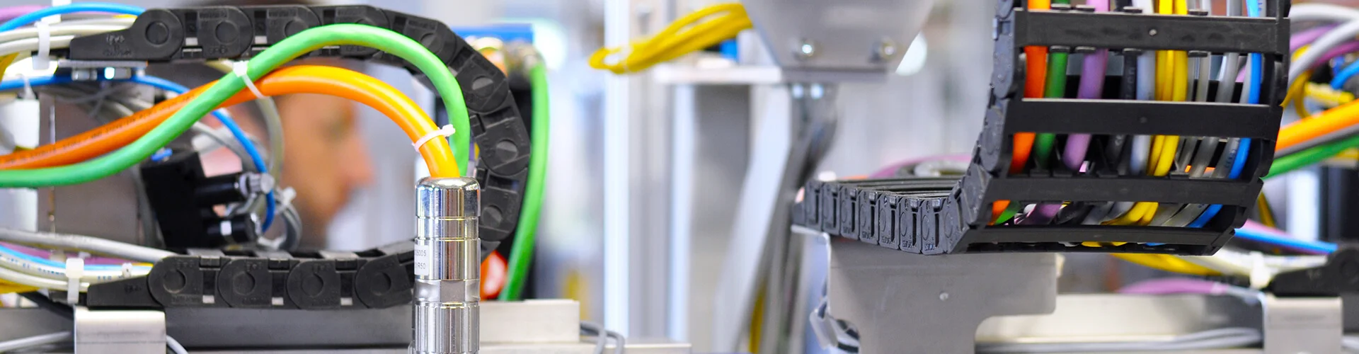 Diverse Kabel, die mithilfe von Schleppketten verlegt wurden und an den durch Kabelkonfektion Stecker angebracht sind.