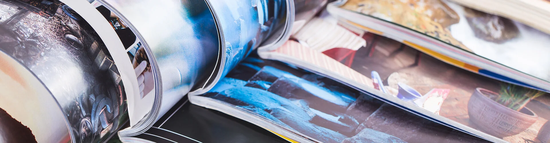 Zeitschriften und Magazine, die aufgeschlagen ineinander gereiht liegen.