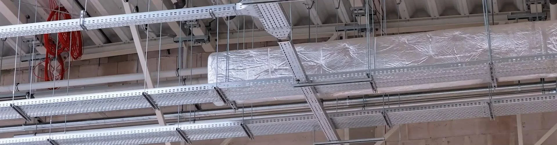 Verschieden breite Kabelrinnen, die als Kabeltrassen auf verschiedenen Höhen an der Decke eines Lager befestigt sind.